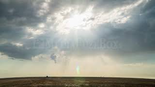 Stock Video - Time lapse of sun rays shining through the clouds moving over flat landscape