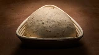 Bread dough rising in a proofing wooden basket time lapse