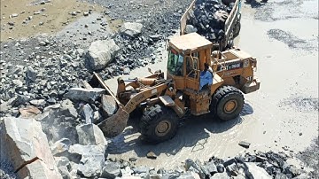 Heavy machine rocks loading in action: caterpillar loader 966E rocks loading trolleys and dampers