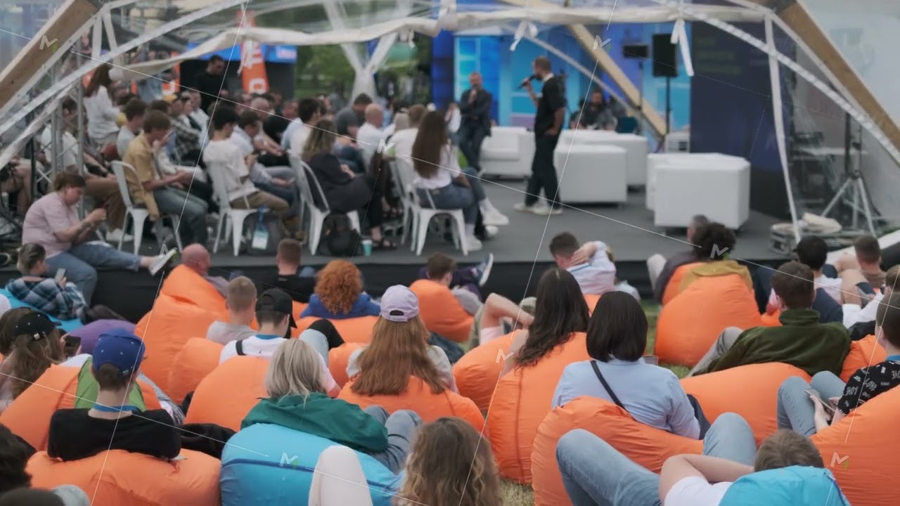 Outdoor audience seated on beanbags during a speaker presentation at an event