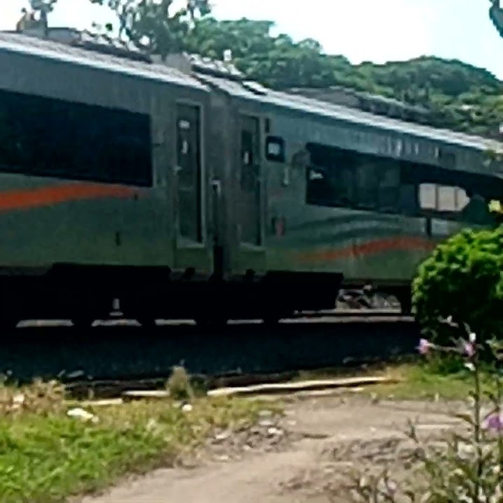 liat lokomotip kereta api lagi deket pintu perlintasan.