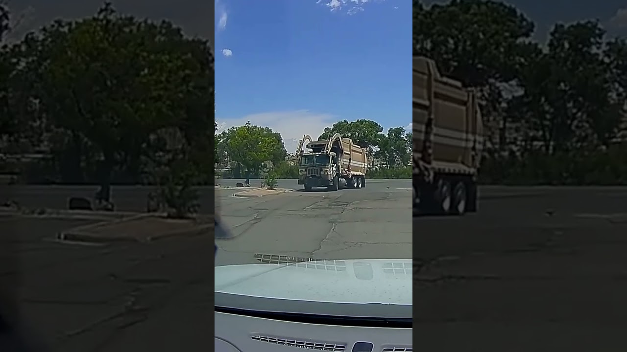 Large Frontend Hydraulic Loader Garbage Trash Truck turning into commercial parking lot