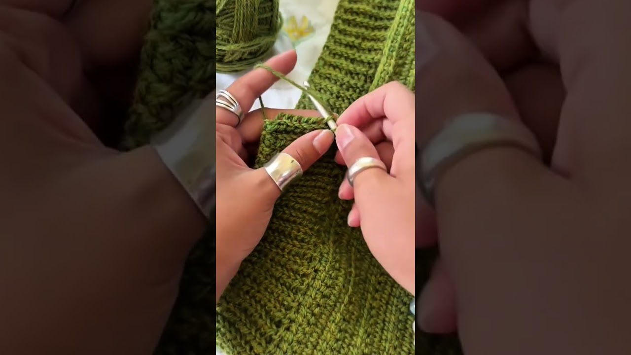 knitting a green woolen fabric using a metal crochet hook with a ball of yarn in indoor room area