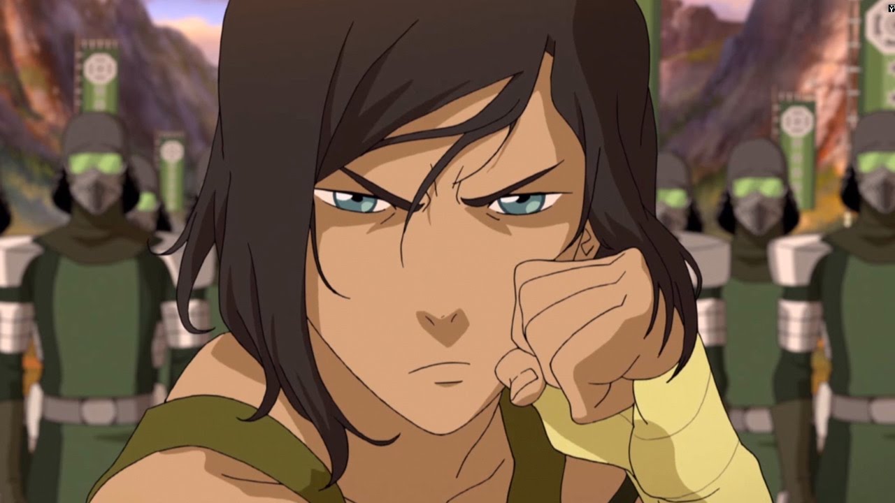 The Legend of Korra season 4. A close up of Korra, her dark hair falling over her face and her eyebrows furrowed in a blue-eyed glare directly into the camera. Her bandaged fist is raised to her face, she looks ready to fight.