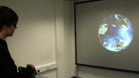 Ruairi using a Wii remote to manipulate a 3-D map of the Earth.