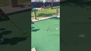 Kids play miniature golf then little boy runs to get ball and faceplants near hole