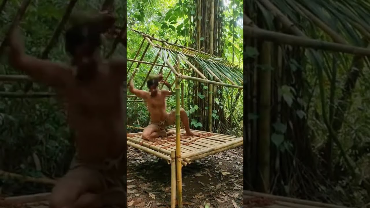 man building a jungle survival house by hand from bamboo, wood, and leaves, cutting, tying, roofing