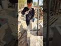 A worker chisels a large stone with a simple technique but achieves neat, precise results