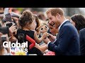 Children hand Prince Harry and Meghan Markle stuffed toys during Auckland meet and greet