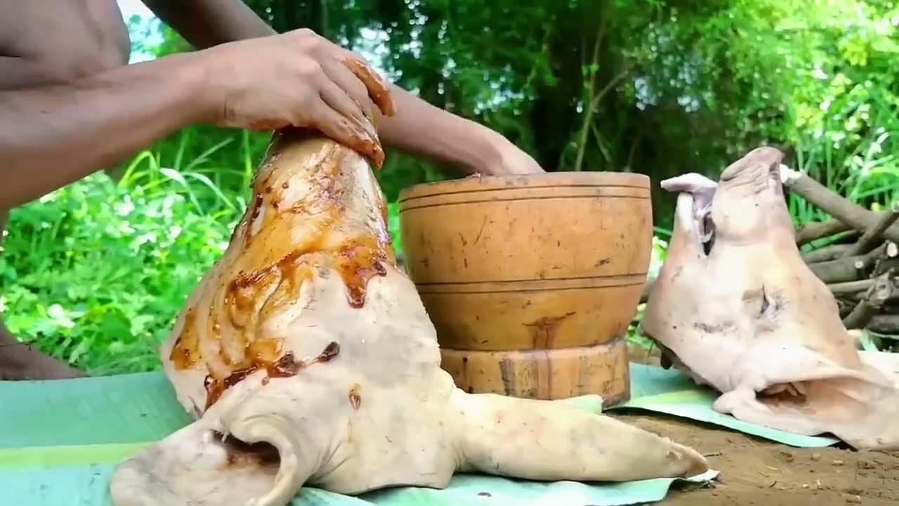 Two young men show off their homemade roasted pig's head outdoors 