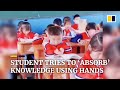 Student in china tries to absorb knowledge from book using hands