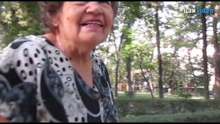 Бабушка рвет цветы в парке Т. Молдо в бишкеке