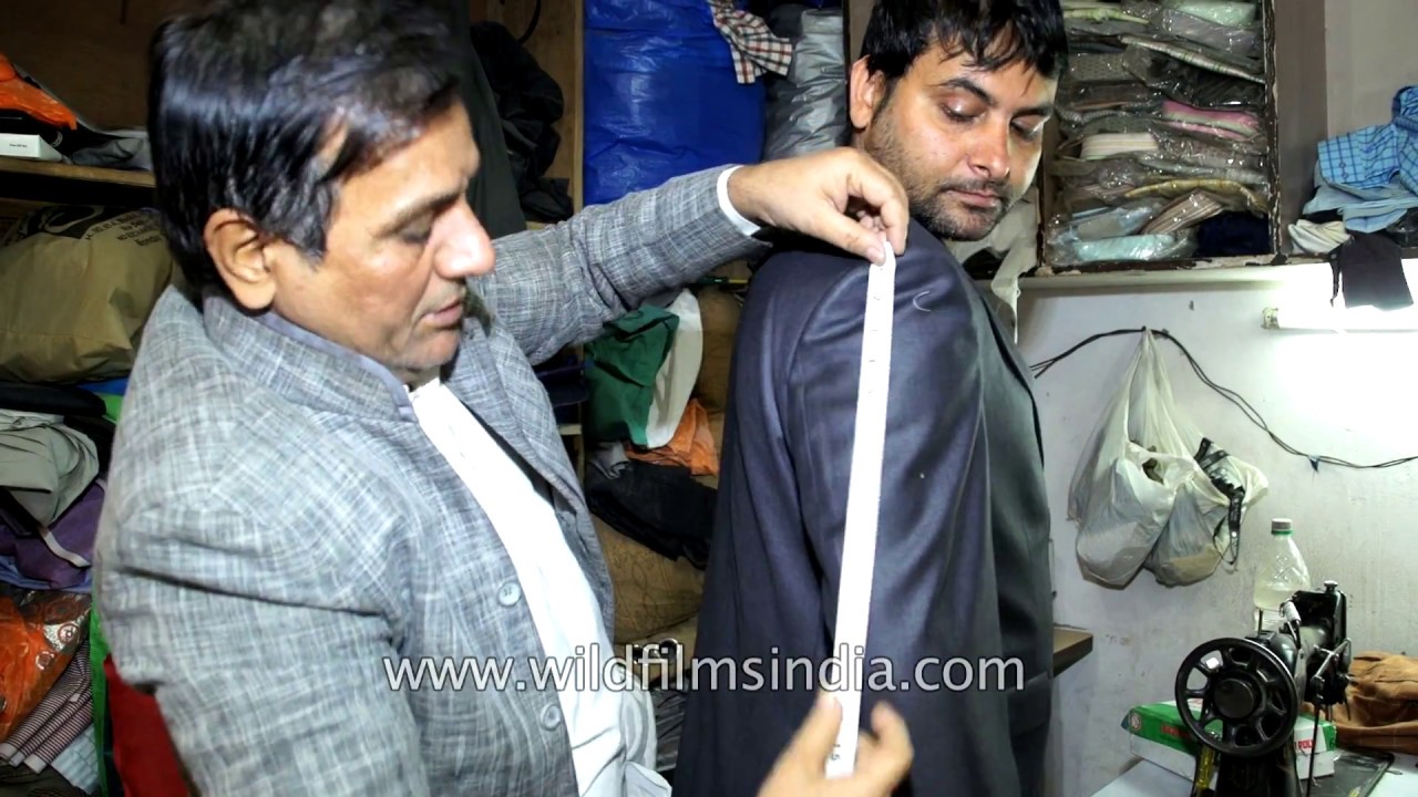 Indian tailor at work, masterji measures client for fit-out