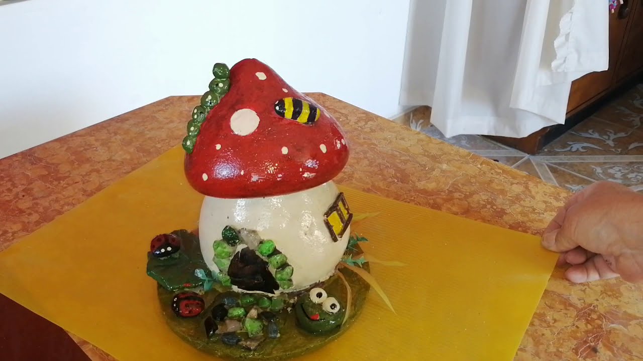 Artesanía.  Casa de hadas de cemento  en forma de hongo, con varios insectos.