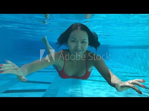 Woman swimming underwater in a blue pool.