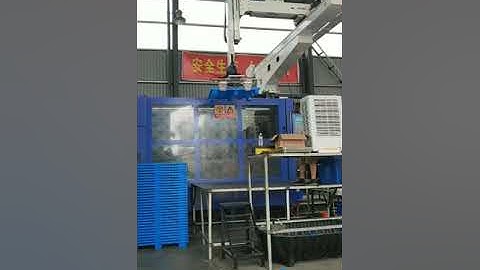 Robot picking up pallet  from big injection molding machine