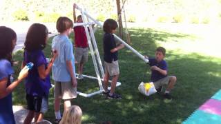 Elementary school kids firing off a trebuchet in a castle siege demonstration for school. Here