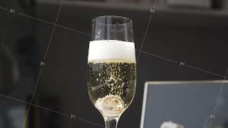 Wedding rings fall into a glass of champagne on a black background. Slow motion. Transparent glass