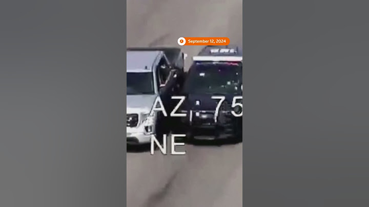Policjant wsiada do jadącego pojazdu, aby pomóc kierowcy