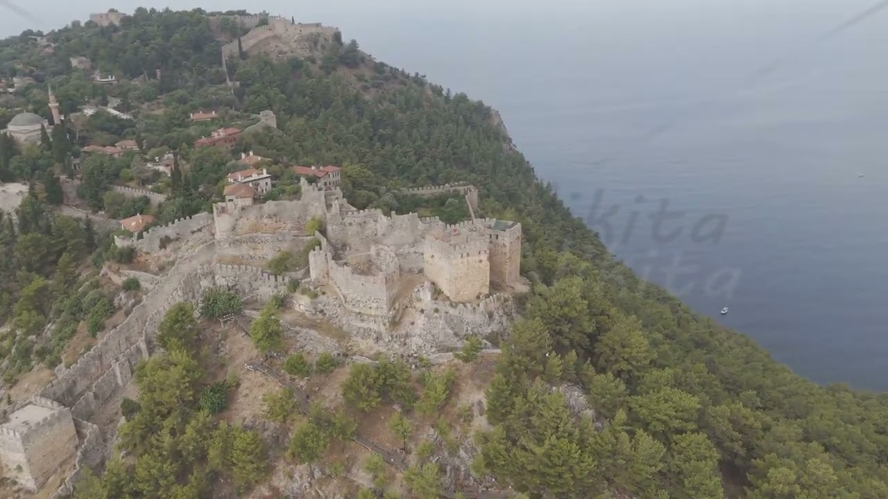 D-Log M. Alanya, Turkey. Ehmedek Castle emerging from green forest on mountainside, aerial drone ...