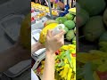 peeling a fresh mango with a peeler at a fruit stall in the market