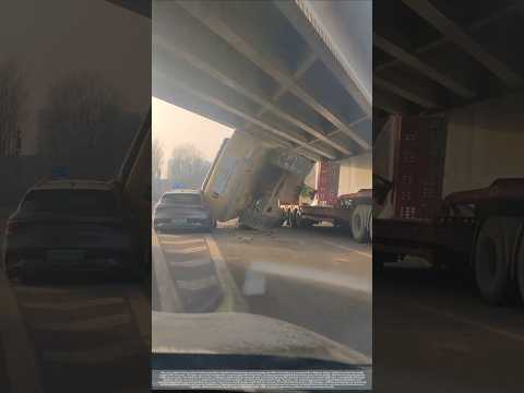 A trailer truck mishandled while crossing a bridge, turning the excavator into a roadblock.