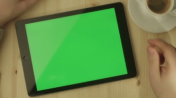tablet with green screen laying on a wooden table in landscape mode
