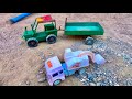 A mini JCB is used to load sand into a tractor trailer and push it