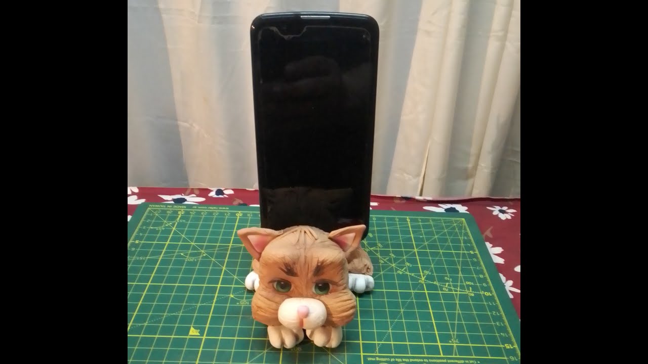 Gato apoya celular en porcelana fria