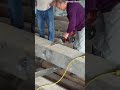 cutting a thick wooden beam precisely using an electric chainsaw while creating lot of sawdust