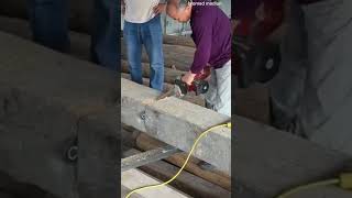 cutting a thick wooden beam precisely using an electric chainsaw while creating lot of sawdust
