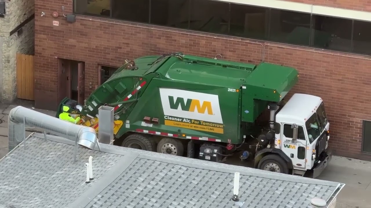 A Waste Management Peterbuilt 520 CNG McNeilus rear loader picking up garbage in downtown.