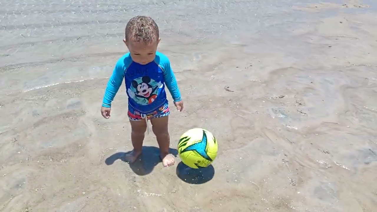 Lukinha jogando bola na praia.