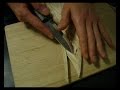 Carving a pattern on a board with a knife.