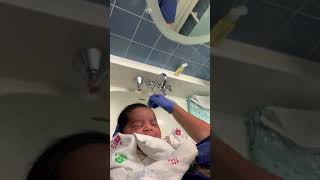 New born baby with long hairs enjoys his 1st hair wash