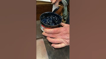 Rolling out green rubber base ink with a brayer on a galley tray for letterpress printing