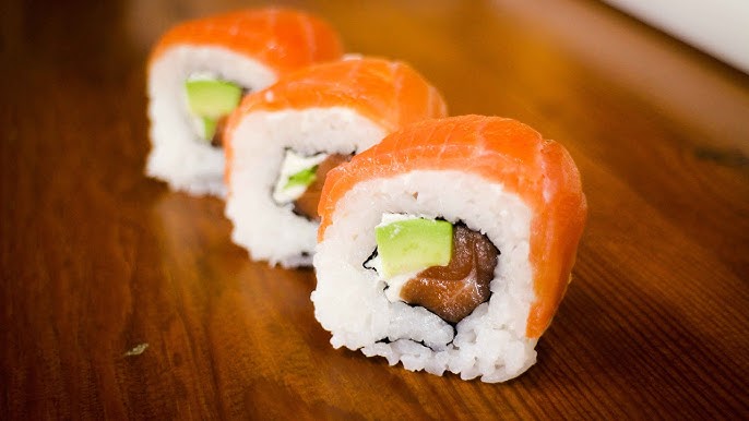 Sushi Roll Salmon segar dengan potongan alpukat dan mentimun, disajikan dengan biji wijen panggang