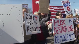 Demonstrators gather outside Tesla dealership during global day of protest against Musk's involvemen