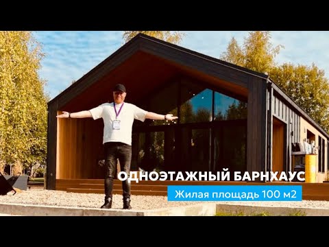 Одноэтажный барнхаус из дерева с большими окнами на фоне осенних деревьев