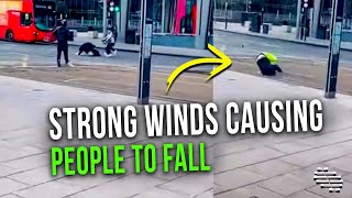Strong Winds Causing People to Fall as Others Try to Take Shelter and Help Those in Need
