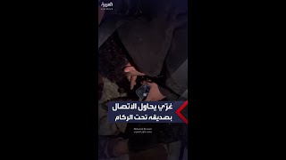 شاب غزّي يحاول الاتصال بصديقه بعد أن دُمر منزله وعلق تحت الركام