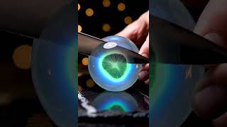 rotational slow knife slice through glass-like fruit revealing glowing translucent concentric rings
