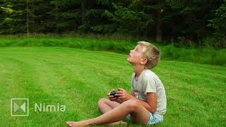 Young Boy Flying Small Drone Sitting On Lawn