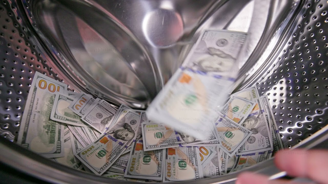hand is inserting the US Dollar banknotes inside a washing machine drum