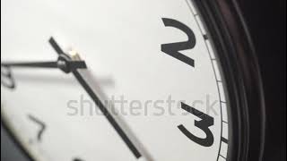 Closeup of White Clock Face in timelapse in daytime of office dark grey wall