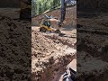 Excavator operator bedding a plastic water storage tank with crusher fines