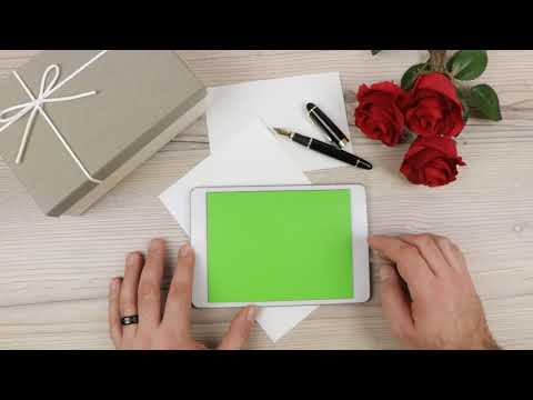 a man using a Tablet PC with green empty screen on a wooden table - free use @bestgreenscreen