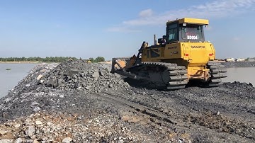 The SHANTUI DH17c2 Bulldozer Machine Pushing Rock For Backfill Uploading Dump Truck On Construction.