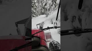 Tractor with front mount snow blower blowing some snow.