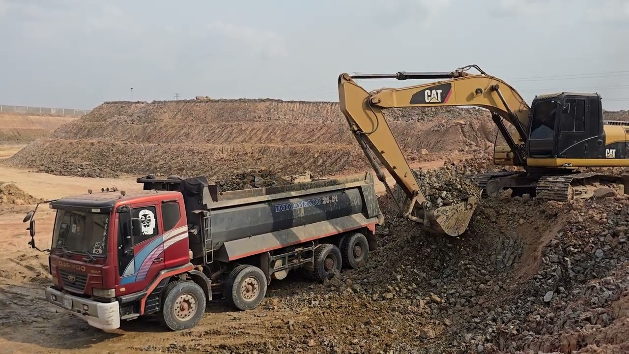 A CAT 320 GC excavator is loading soil into a 12-wheel Hyundai truck from Korea.